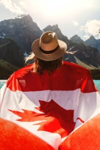 A woman wearing Canadian flag as a cape ,looking at nature with her back towards camera